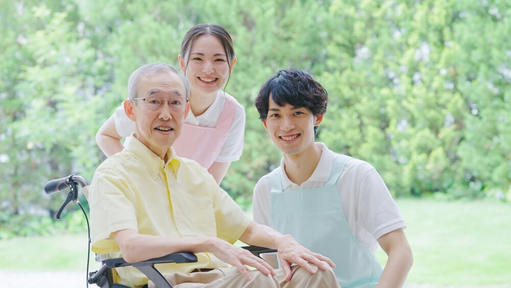 2人の若い介護士と高齢者が笑顔で映る写真